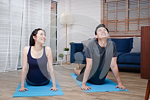 Asian couples exercise together at home in the living room.