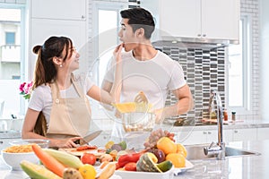 Asian couples feeding food together in kitchen. People and lifestyles concept. Sweet honeymoon and Holidays concept. Valentines d photo