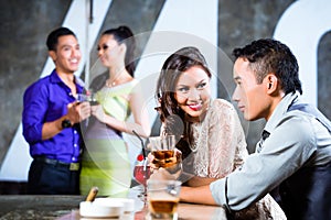 Asian couples flirting and drinking at nightclub bar