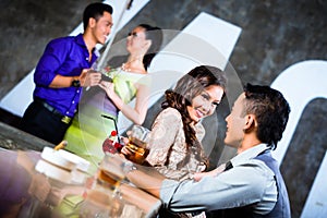 Asian couples flirting and drinking at nightclub bar