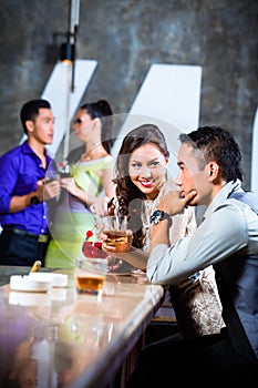 Asian couples flirting and drinking at nightclub bar