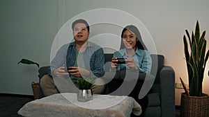 Asian couples are having fun playing games in their living room at night
