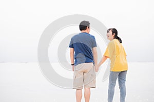 Asian couples holding hands together on a private beach by the sea background. Happy man and woman laughing together on travel