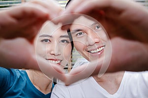 Asian couples make happy heart-shaped hands in their new home.