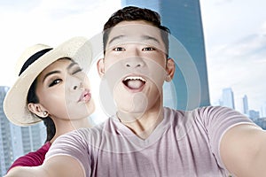Asian couples making a selfie with a funny face using a camera phone