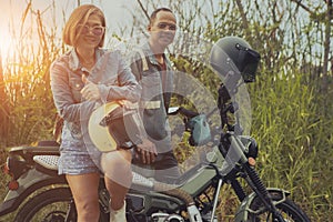 asian couples standing beside enduro motorcycle with high green grass background