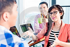 Asian creative agency workers discussing