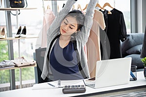 Asian creative designer stretching arms and close eye in front of laptop computer on work desk