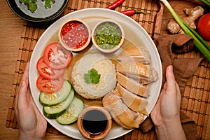 Asian cuisine concept. Female hands in close-up holding Hainanese chicken rice