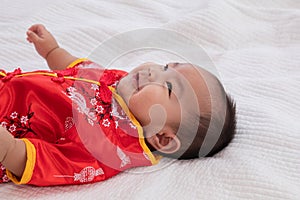 Asian cute baby boy Chinese Cheongsam costume toddler lie down on bed at home smiling laughing good humored  infant Chinese