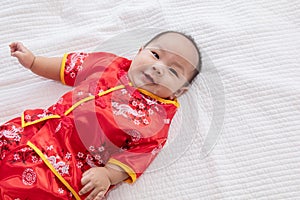 Asian cute baby boy Chinese Cheongsam costume toddler lie down on bed at home smiling laughing good humored  infant Chinese