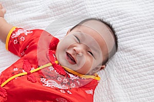 Asian cute baby boy Chinese Cheongsam costume toddler lie down on bed at home smiling laughing good humored  infant Chinese