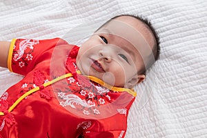 Asian cute baby boy Chinese Cheongsam costume toddler lie down on bed at home smiling laughing good humored  infant Chinese