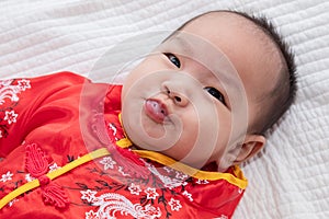 Asian cute baby boy Chinese Cheongsam costume toddler lie down on bed at home smiling laughing good humored  infant Chinese