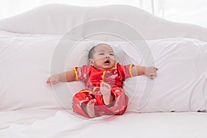 Asian cute baby boy Chinese Cheongsam costume toddler lie down on bed at home smiling laughing good humored  infant Chinese