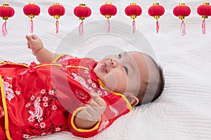 Asian cute baby boy Chinese Cheongsam costume toddler lie down on bed at home smiling laughing good humored  infant Chinese boy