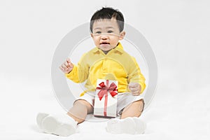 Asian cute baby boy about one year old in yellow shirt have fun smile and laugh happily with gifts and toys isolated on white