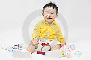 Asian cute baby boy about one year old in yellow shirt have fun smile and laugh happily with gifts and toys isolated on white