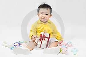 Asian cute baby boy about one year old in yellow shirt have fun smile and laugh happily with gifts and toys isolated on white