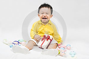 Asian cute baby boy about one year old in yellow shirt have fun smile and laugh happily with gifts and toys isolated on white