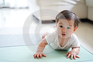 Asian cute baby crawling on soft carpet or mat at home.