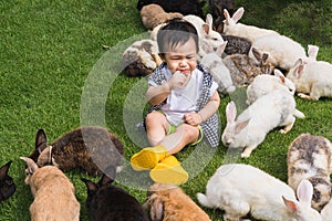 Asian cute boy sucking fingers and crying on the lawn among the surrounding rabbits