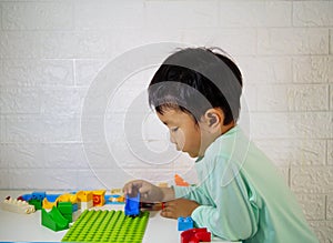 Asian cute child boy playing block lego at home. Kid learning to build toy.