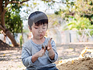 Asian cute child boy playing clay outdoor with funny face in garden.