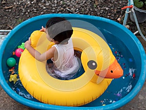 Asian cute child boy playing water in blue bowl in rural nature. Young kid having happy moment in summer.