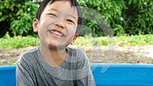 Asian cute child boy smiling and laughing with whitening teeth in nature background.