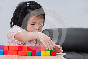 Asian cute child playing colorful wood blocks stack game. Learning and development concept. Little girl aged 4-5 years old