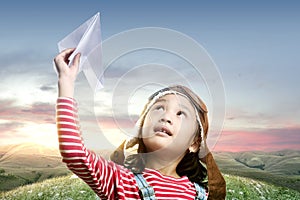 Asian cute girl in an aviator cap with a paper plane with a sunset sky background