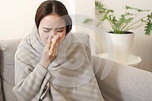 Asian Cute of  girl having  flu season  and  sneeze  using paper tissues sitting on sofa at home, Putting blanket, Health and photo