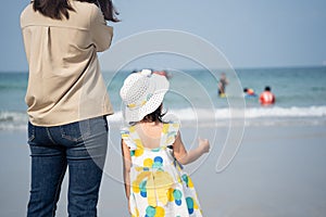 Asian cute girl and her mother walking or running or playing on the beach on summer holidays. Children with beautiful sea, sand