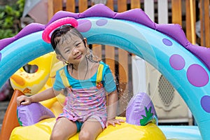 Asian cute girl playing in inflatable baby pool