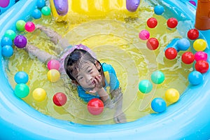 Asian cute girl playing in inflatable baby pool