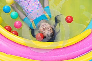 Asian cute girl playing in inflatable baby pool