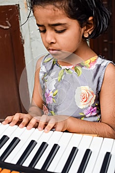 Asian cute girl playing the synthesizer or piano. Cute little kid learning how to play piano