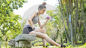Asian cute healthy fit and firm slim lady happy to sitting workout with small dumbbell in position bicep curls lifting  at outdoor