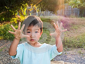 Asian cute little child boy showing dirty hands with sand while playing outdoor.