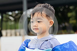 Asian cute little toddler boy in a colorful swimming suit relaxing in a pool