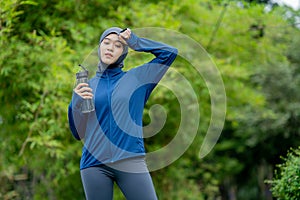 Asian cute muslim woman wearing sportswear and a blue hijab Exercising and running outdoors at the park