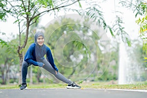 Asian cute muslim woman wearing sportswear and a blue hijab Exercising and running outdoors at the park in the morning.