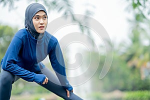 Asian cute muslim woman wearing sportswear and a blue hijab Exercising and running outdoors at the park in the morning.