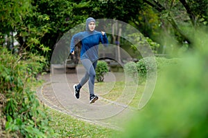 Asian cute muslim woman wearing sportswear and a blue hijab Exercising and running outdoors at the park in the morning.