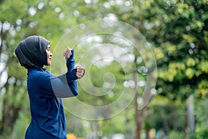 Asian cute muslim woman wearing sportswear and a blue hijab Exercising and running outdoors at the park in the morning.