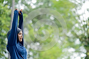 Asian cute muslim woman wearing sportswear and a blue hijab Exercising and running outdoors at the park in the morning.