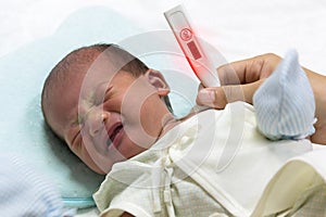 Asian cute new born baby check temperature with digital thermometer.