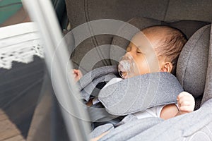 Asian cute newborn baby sleeping in modern car seat.