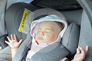 Asian cute newborn baby sleeping in modern car seat.